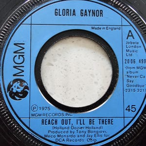 Puede incluir: Etiqueta de disco de vinilo de 45 RPM para la canción "Reach Out, I'll Be There" de Gloria Gaynor. La etiqueta es azul con texto negro y un centro blanco. El disco fue fabricado en Inglaterra y lanzado en 1975.
