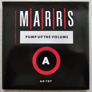Puede incluir: Funda de álbum negra con la palabra MARRS en letras blancas con líneas verticales rojas. El texto "PUMP UP THE VOLUME" está en un rectángulo blanco. Un círculo rojo con una "A" blanca está en la parte inferior. El texto "AD 707" está en la parte inferior.