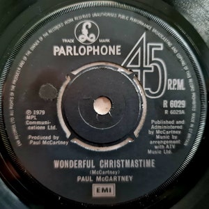 May include: Black and white 45 RPM record label with the text "PARLOPHONE" and "WONDERFUL CHRISTMASTIME (McCartney) PAUL MCCARTNEY" in white. The label also includes the text "EMI" in white.