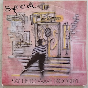May include: Album cover for Soft Cell's "Say Hello Wave Goodbye." The artwork features a sketched illustration of a person in a striped shirt and dark pants, standing before a stylized building entrance. The cover has a pink background with the band's name and song title.