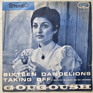 Op de afbeelding: Een vintage platenhoes met een vrouw met donker haar en een wit kanten topje die een boeket bloemen vasthoudt. De hoes is getiteld "Sixteen Dandelions Taking Off (I Believe In Love) (dal film omonimo)" en toont de naam van de artiest "GOUGOUSH" in grote, vetgedrukte letters.