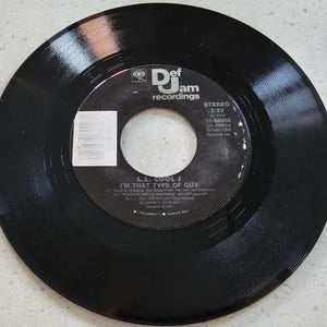 May include: Black vinyl record single by L.L. Cool J, titled "I'm That Type of Guy." The record label features the Def Jam Recordings logo and details including the song's duration, 3:23, and speed, 45 RPM. The record is a stereo recording.