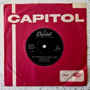 Könnte beinhalten: Eine rote Vinyl-Plattenhülle mit weißem Text, der "CAPITOL" und "I'LL NEVER FALL IN LOVE AGAIN" von Bobbie Gentry lautet. Das Plattenlabel ist schwarz mit weißem Text und einer kleinen amerikanischen Flagge.