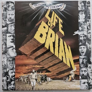 May include: Album cover for Monty Python's "Life of Brian." The artwork features a large, stylized, yellow and brown brick structure with the title. The cover includes a collage of faces and a scene of people walking in a desert landscape.