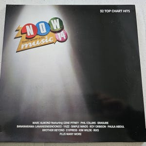 Peut inclure: Une pochette de CD pour l'album "NOW That's What I Call Music 14". La couverture présente le mot "NOW" en rouge, bleu et vert, avec "music 14" en rose. L'album contient 32 succès.
