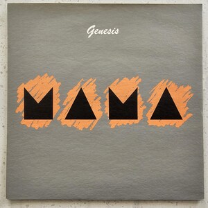 May include: A gray album cover with the band name "Genesis" in white script at the top. The word "MAMA" is spelled out in black geometric shapes with orange brushstroke accents.