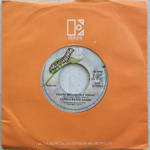May include: A vintage 45 RPM vinyl record by Carole Bayer Sager, titled "You're Moving Out Today." The record label features a caterpillar on a leaf design. The record is housed in an orange Elektra Records sleeve.
