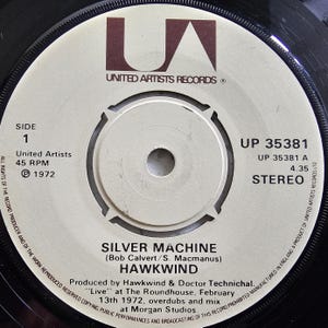 May include: Close-up of a vintage vinyl record label. The label is cream-colored with black text and a brown logo for United Artists Records. The text reads "Silver Machine" by Hawkwind, with production details and a 1972 copyright.