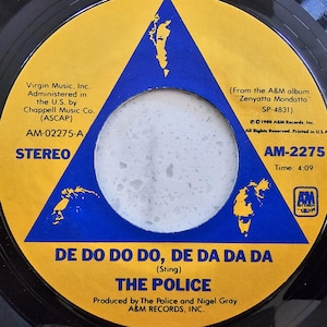 May include: A vinyl record for the song "De Do Do Do, De Da Da Da" by The Police. The record label is yellow and blue with the band's name and song title. The label also includes the album title, time, and record company information.