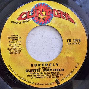 May include: A vintage vinyl record with a yellow and black label. The label features the text "SUPERFLY" by Curtis Mayfield, the Curtom Records logo, and other details. The record is from the motion picture soundtrack.