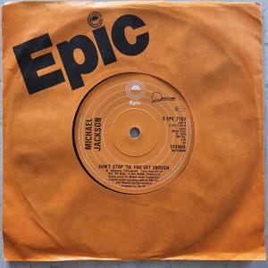 Può includere: Un disco in vinile vintage di Michael Jackson, intitolato "Don't Stop 'Til You Get Enough", nella sua custodia originale arancione Epic Records. L'etichetta del disco è arancione e bianca con testo nero.