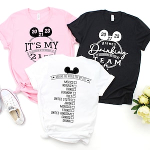 May include: Three t-shirts with a Disney theme. The pink shirt says "It's My 21st", the black shirt says "Disney Drinking Team", and the white shirt says "Around the World for My 21st" with a checklist of countries.