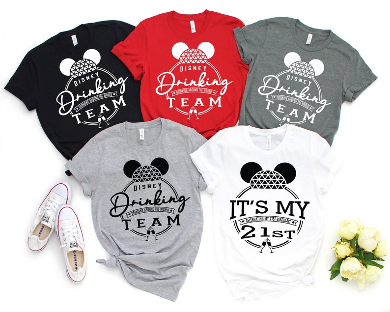 May include: Five t-shirts with a black and white graphic of Mickey Mouse ears with the Spaceship Earth icon inside. The shirts are black, red, grey, white, and heather grey. The text on the shirts reads "Disney Drinking Team" and "It's My 21st".