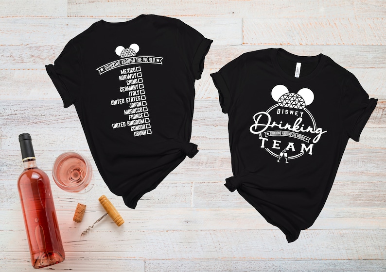 May include: Two black t-shirts with white text and graphics. One shirt says "Drinking Around the World" with a list of countries and checkboxes. The other shirt says "Disney Drinking Team" with a Mickey Mouse ear silhouette and a Spaceship Earth graphic.