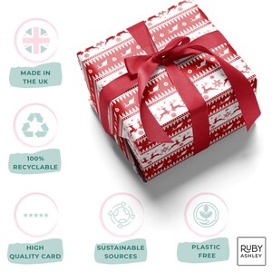May include: A wrapped gift box with a red and white festive pattern featuring reindeer and snowflakes. The box is tied with a wide red satin ribbon and bow. The gift wrap is labeled as high quality and plastic free.