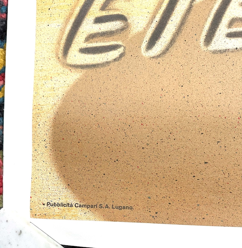 Pode incluir: Um cartaz vintage com fundo amarelo e texto preto que diz "Campari Soda". O texto &eacute; estilizado com uma fonte gr&aacute;fica e em negrito. A parte inferior do cartaz tem o texto "Pubblicit&agrave; Campari S.A. Lugano".