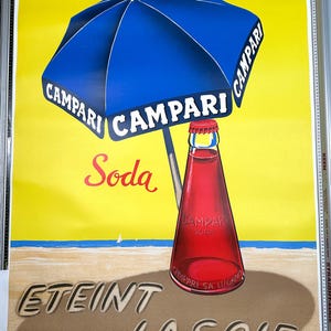 Pode incluir: Um an&uacute;ncio vintage de Campari Soda. A imagem mostra um guarda-sol de praia azul e branco listrado com a palavra "Campari" impressa nele. Uma garrafa de Campari Soda est&aacute; sentada em uma praia de areia com as palavras "Eteint La Soif" escritas na areia.