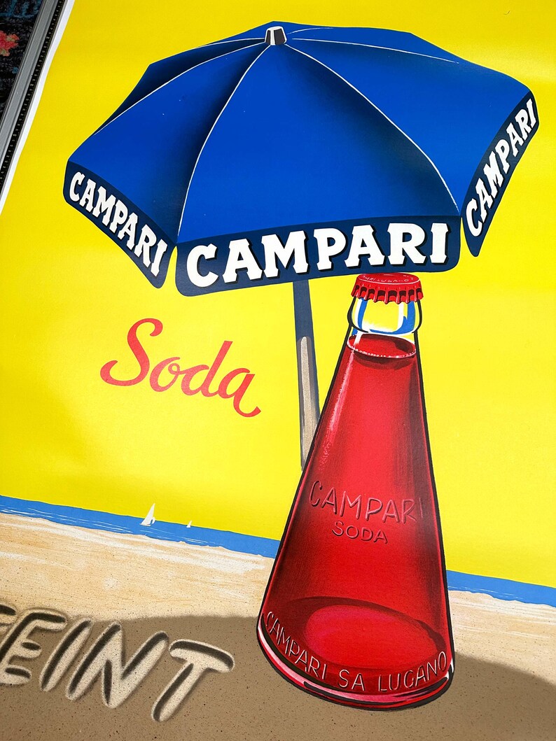 Pode incluir: Um an&uacute;ncio vintage de Campari Soda com um guarda-sol de praia azul e branco listrado com a palavra "Campari" impressa nele. O guarda-sol est&aacute; sobre uma garrafa de Campari Soda em uma praia com as palavras "Campari Soda" impressas na garrafa. O fundo &eacute; um c&eacute;u amarelo e um mar azul.