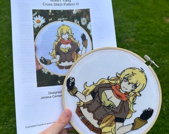 May include: A cross stitch pattern for a character named Yang from the animated series RWBY. The pattern is designed by Jessica Carmen and includes a close-up of the finished cross stitch.