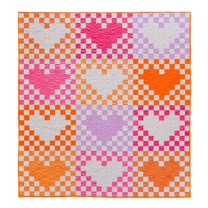 May include: A quilt with a checkered pattern in shades of pink, orange, and white. The quilt is made up of nine squares, each with a different pattern.
