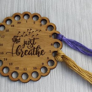 Thread holder in a flower shape with "Just Breathe" engraved, featuring 20 holes for thread.