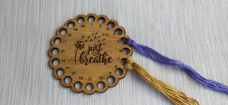 Thread holder in a flower shape with "Just Breathe" engraved, featuring 20 holes for thread.
