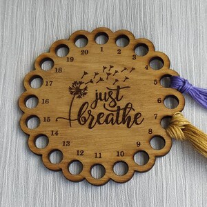 Thread holder in a flower shape with "Just Breathe" engraved, featuring 20 holes for thread.