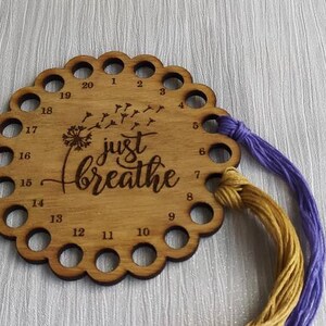 Thread holder in a flower shape with "Just Breathe" engraved, featuring 20 holes for thread.