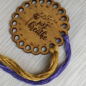 Thread holder in a flower shape with "Just Breathe" engraved, featuring 20 holes for thread.