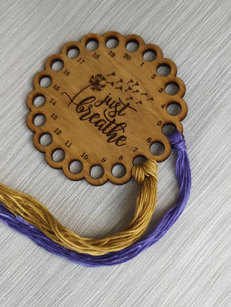 Thread holder in a flower shape with "Just Breathe" engraved, featuring 20 holes for thread.