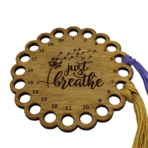 Thread holder in a flower shape with "Just Breathe" engraved, featuring 20 holes for thread.