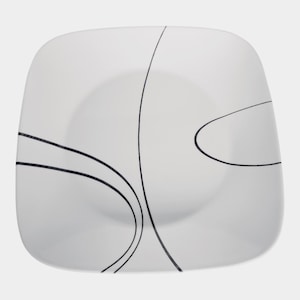 Puede incluir: Una taza de cerámica blanca con un asa negra y el texto "But First, Coffee" en negrita negra. La taza está sobre un fondo neutro, resaltando su diseño simple.