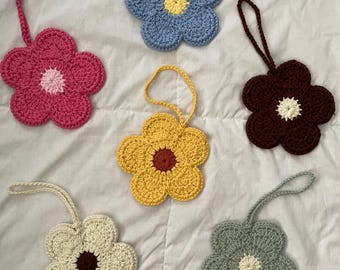 May include: Six crocheted flower ornaments with different colored centers and loops for hanging. The flowers are in shades of blue, pink, yellow, brown, cream, and green.