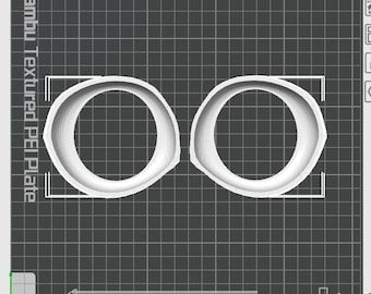 May include: Two white, round, 3D printed objects with a textured surface. The objects are similar to a ring or a donut shape. The objects are printed on a textured surface. "Bambu Textured PEI Plate" is written on the left side of the image.