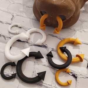 May include: A set of six body jewelry pieces in three different colors: black, white, and gold. Each piece is a curved barbell with pointed ends and a circular shape.