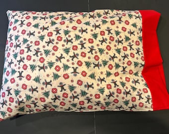 May include: A white pillowcase with a red border. The pillowcase has a repeating pattern of gingerbread men and Christmas trees.