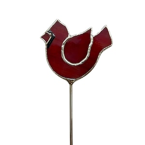 May include: A red stained glass cardinal bird with a silver wire stem. The cardinal is facing the right side of the image.