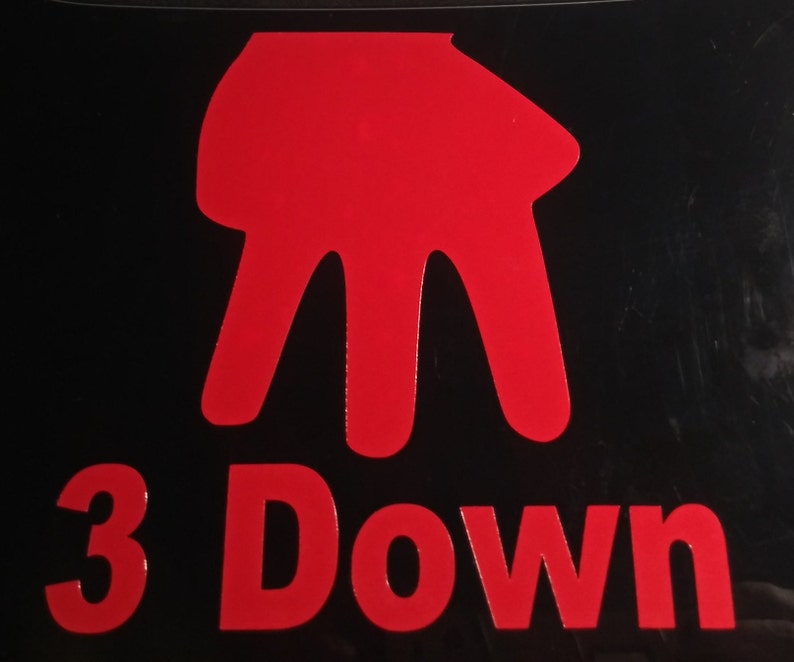 Peut inclure: Fond noir avec un symbole de main rouge et les mots "3 Down" en rouge. Le symbole de la main a trois doigts pointant vers le bas. Le texte est en gras, sans empattement.