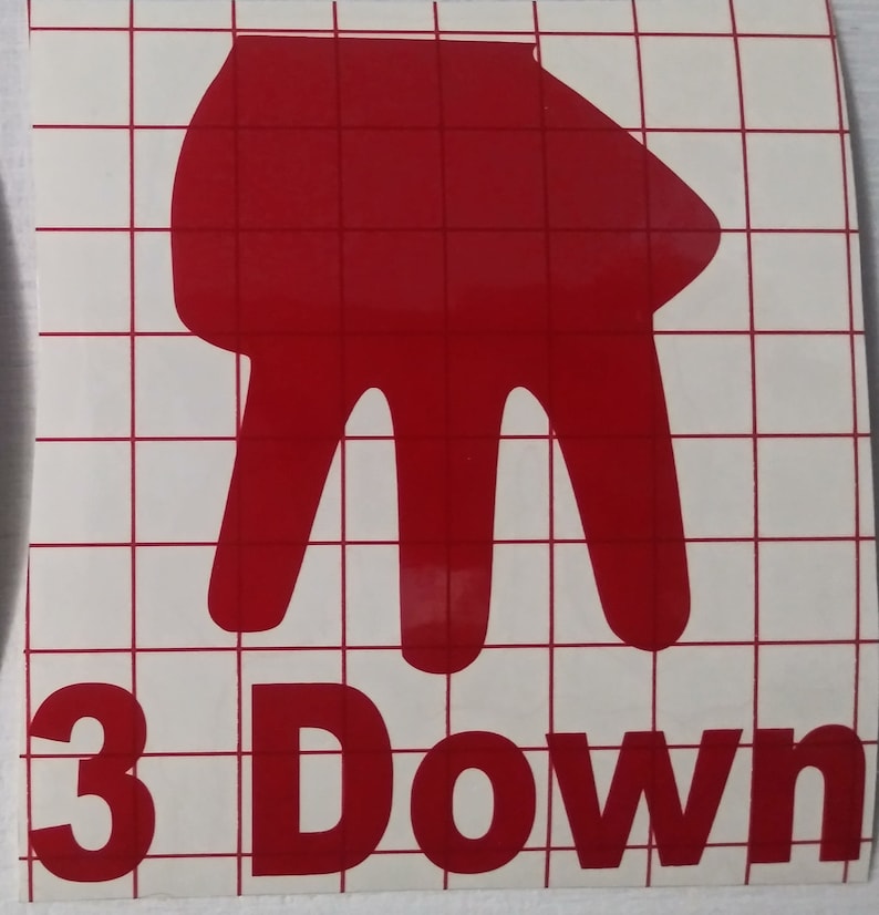 Peut inclure: Un autocollant en vinyle rouge repr&eacute;sentant un geste de la main avec trois doigts pointant vers le bas, au-dessus des mots "3 Down" en rouge. L'autocollant est sur un fond blanc avec un motif quadrill&eacute;.