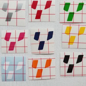 May include: Nine different colored vinyl stickers with a geometric design. The stickers are on a white gridded background.