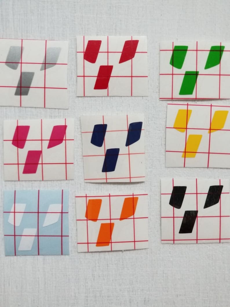 May include: Nine different colored vinyl stickers with a geometric design. The stickers are on a white gridded background.