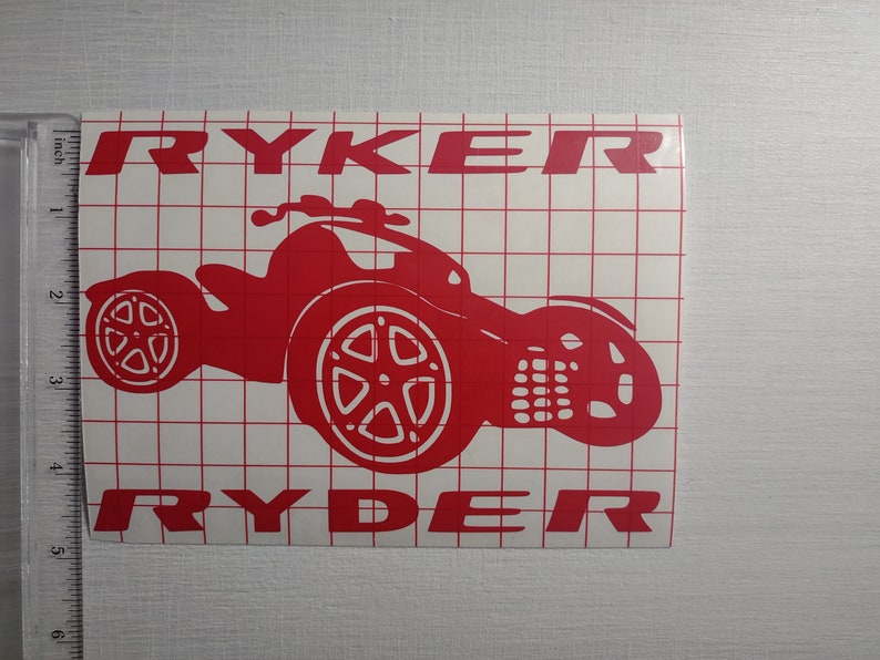 May include: Red vinyl decal with the name "RYKER" at the top and the name "RYDER" at the bottom. A red silhouette of a three-wheeled vehicle is in the center.