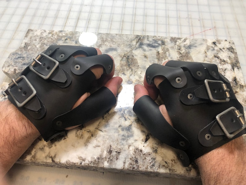 May include: A pair of black leather fingerless gloves with multiple buckles and metal accents.