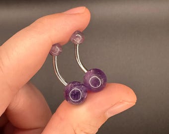 Peut inclure: Deux anneaux de nombril en argent avec des pierres précieuses d'améthyste violettes.