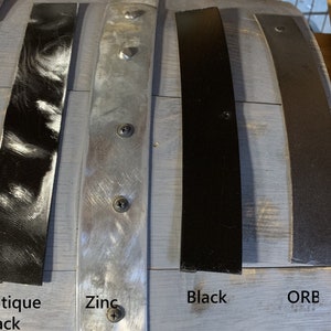 Pu&ograve; includere: Primo piano di quattro strisce di metallo in diverse finiture: nero anticato, zinco, nero e bronzo oliato. Le strisce sono etichettate sotto con le loro rispettive finiture.