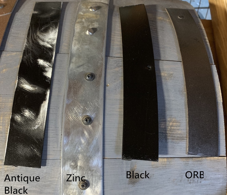 Pu&ograve; includere: Primo piano di quattro strisce di metallo in diverse finiture: nero anticato, zinco, nero e bronzo oliato. Le strisce sono etichettate sotto con le loro rispettive finiture.