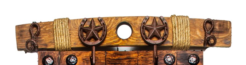 Pu&ograve; includere: Un appendiabiti in legno rustico con cinque ganci, con un design a forma di ferro di cavallo e stella. L'appendiabiti &egrave; realizzato in legno riciclato e ha una finitura naturale. &Egrave; decorato con corda e dettagli in metallo.