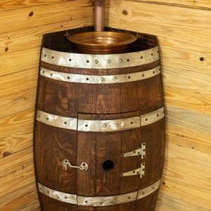 May include: A wooden barrel sink with a copper basin and a metal faucet. The barrel is decorated with metal bands and has a small door on the front.