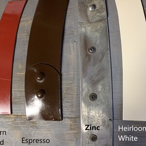 Pu&ograve; includere: Primo piano di cinque diversi campioni di vernice su una superficie di legno. I campioni sono etichettati "Barn Red", "Espresso", "Zinc" e "Heirloom White".