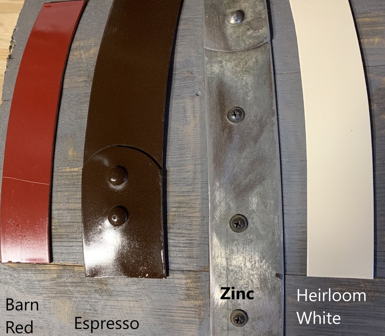 Pu&ograve; includere: Primo piano di cinque diversi campioni di vernice su una superficie di legno. I campioni sono etichettati "Barn Red", "Espresso", "Zinc" e "Heirloom White".